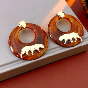 Macro detail of amber resin hoop earrings featuring a golden leopard ornament