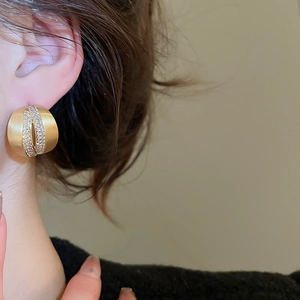 Macro shot of 18K gold brushed metal C-shape earring with sparkling zircon inlay
