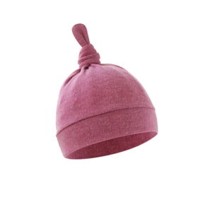 Detail of pink knotted baby beanie made from soft cotton material on white background