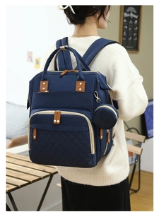 Detail of navy blue mommy bag with quilted front pocket and brown leather pull tabs