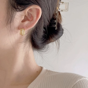 Close-up of a model wearing a gold twisted rope textured hoop earring in a clean setting