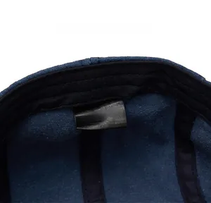 Macro view of the 100% cotton care label and stitching inside the navy blue newsboy cap