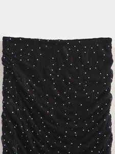 Détail du tissu plissé noir avec des strass argentés brillants et texture douce