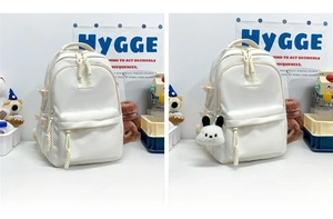 Comparison showing standard off-white backpack and variant with cartoon dog pendant