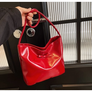 Detail of red leather bucket bag featuring a decorative bow and elegant single handle