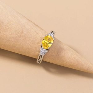 Detailed macro view of silver ring with yellow oval gemstone on a wooden cone stand