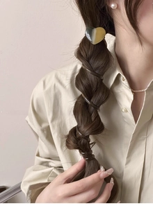 Detailed view of a brown spiral telephone wire hair tie wrapped around a ponytail