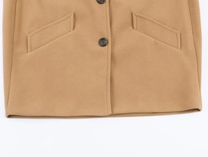 Detail view of camel wool coat hem featuring dark resin buttons and symmetrical flap pockets