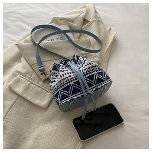 Detail of blue and white geometric fabric bucket bag with leather strap on soft blazer