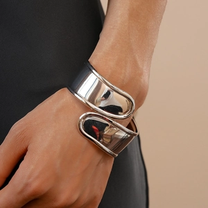Polished silver metal wide cuff bracelet with asymmetric fluid design on model wrist