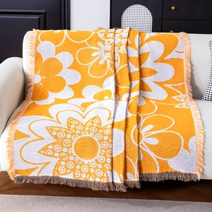 Floral knit throw blanket with yellow fringe draped on a cozy white sofa