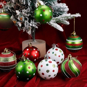 Detail of red and green glitter Christmas ornaments hanging on a snowy tree branch