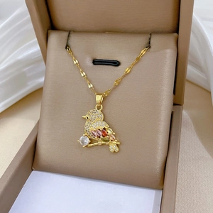 Macro detail of bird pendant with colorful gemstones and pavé zirconia in a beige gift box