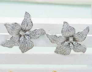 Luxurious silver floral earrings with sparkling cubic zirconia on a minimalist white stand