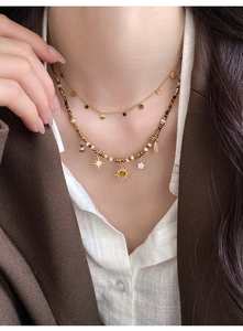 Detail of layered tiger eye beaded necklace with gold sun and star charms on model