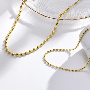 Detailed close-up of 3mm and 5mm golden olive bead necklaces on a glass display