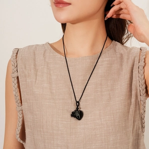 Black heart pendant necklace on braided rope shown on model in minimalist vintage style