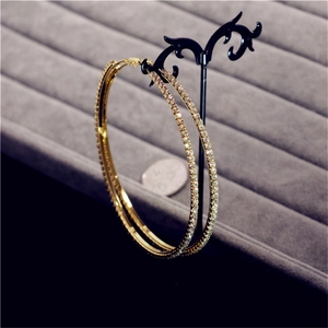 Close-up of gold oversized hoop earrings with sparkling rhinestones on display stand