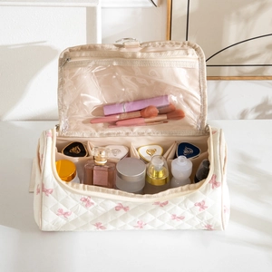 White quilted makeup bag with pink bow embroidery featuring multi-compartment interior