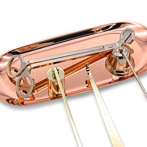 Rose gold metal tray set with silver wick trimmer, gold snuffer and wick hook on white background