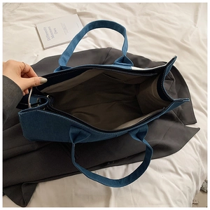 Deep blue denim tote bag detail showing internal compartment and wide handles