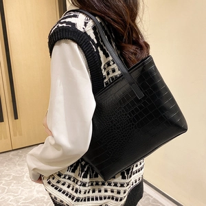 Classic black crocodile pattern hobo tote bag worn by model in a minimalist setting