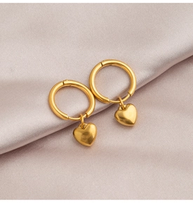Detailed view of gold heart dangle earrings on elegant purple satin fabric background