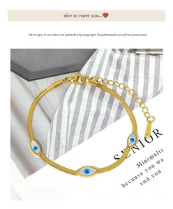 Detailed macro view of gold snake chain bracelet with evil eye pendants and steel stamp