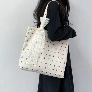 Minimalist beige canvas tote bag with colorful polka dots and white lace bow detail