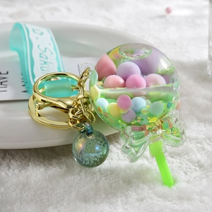 Macro shot of an acrylic lollipop keychain with colorful sequins and a green bow detail