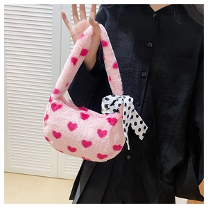 Close-up of pink plush handbag with heart patterns and silk scarf on the handle