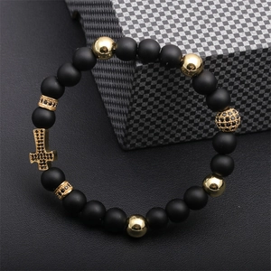 Detail of beaded bracelet showing matte black beads and gold cross with black crystals
