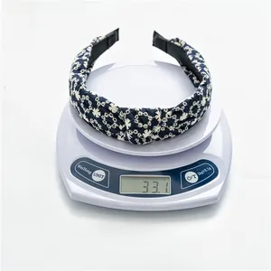 Macro shot of the navy blue embroidered headband with white floral pattern on a scale