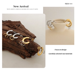 Detail of interlocking gold and silver geometric hoop earrings on minimalist backgrounds