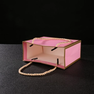 Detailed inner view of pink gift bag with gold trim and braided rope handles
