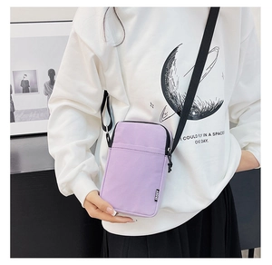 Detail view of a purple nylon mini crossbody phone bag with an adjustable black strap