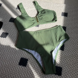 Detail of olive green ribbed bikini with gold metal V-neck hardware and high waist bottom