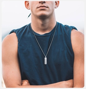 Close-up of a men's rectangular silver pendant necklace worn by a male model