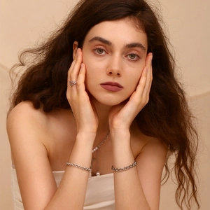Detail shot of a model wearing silver-toned wheat chain bracelets and pearl necklaces