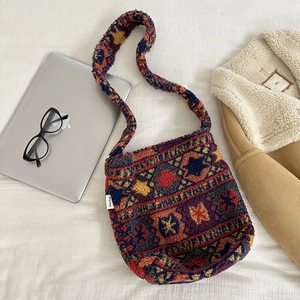 Close-up of ethnic pattern plush crossbody bag with miss bag label on fabric background