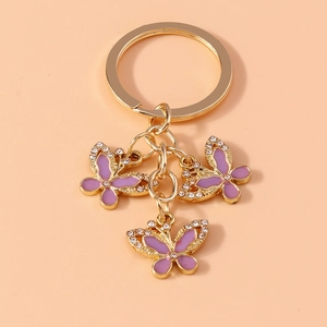 Close-up of golden butterfly keychain with purple enamel wings and sparkling rhinestones