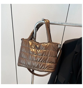 Detail of metallic bronze quilted crossbody bag hanging on a rack with textured finish
