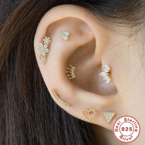 Close-up of 925 sterling silver gold stud earrings with cubic zirconia in heart and crown shapes