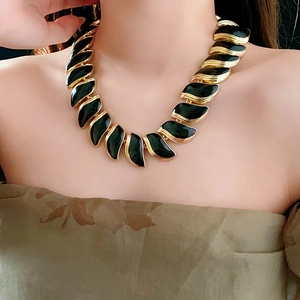 Gros plan du collier feuille vintage doré avec pierre noire sur le mannequin