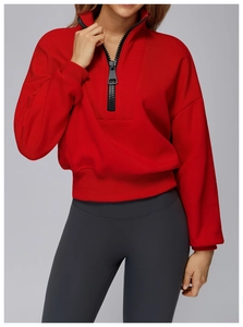Close-up of red half-zip sweatshirt featuring a large black zipper and ribbed cuffs