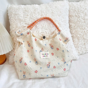 Detail of beige bubble fabric tote bag featuring cute cartoon rabbit and woven rope handle