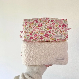Detail of floral cotton and white plush cosmetic bags with zipper closure