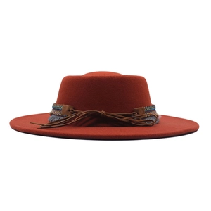 Detail of burnt orange fedora hat featuring ethnic embroidery and brown leather bow strap