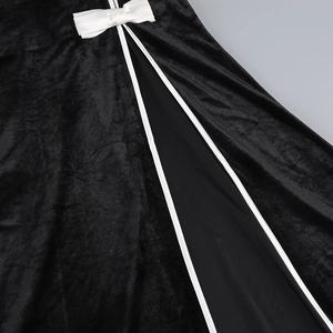 Detail of black velvet dress with white satin bow, high slit, and premium trim design
