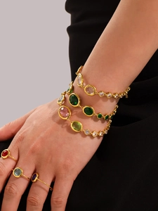 Detail of gold chain bracelet with oval emerald green stones and zircon accents